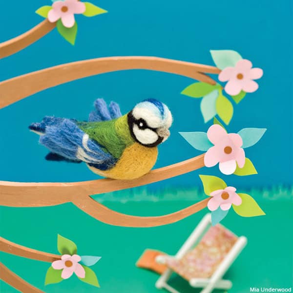A 3D needle felted blue tit model sitting in a tree