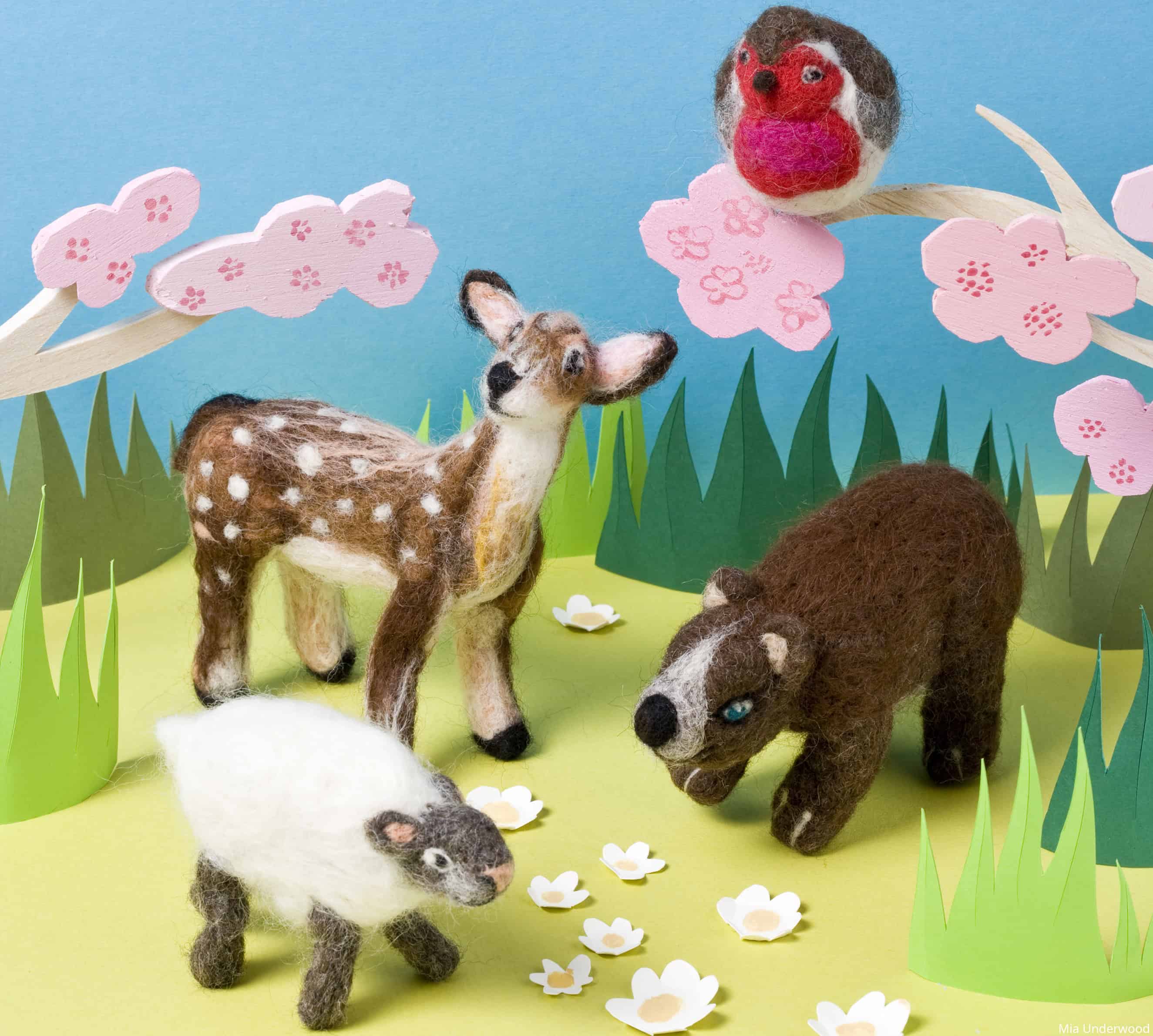 A garden scene with needle felted 3D models of a deer, a sheep, a bear and a robin