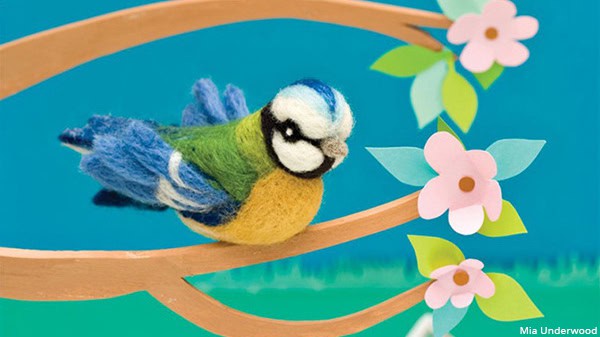 A needle felted 3D blue tit sitting on a crafted blossom tree